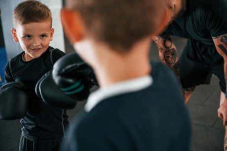 having-fun-by-practicing-young-tattooed-coach-teaching-kids-boxing-techniques_146671-71521